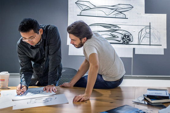 A professor helping a student with a car sketch