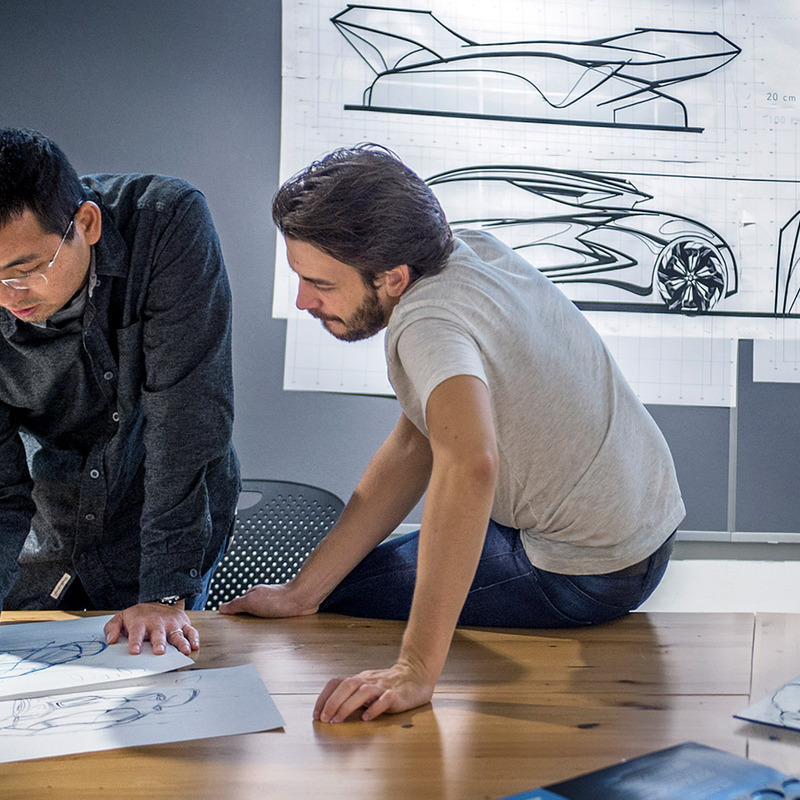 A professor helping a student with a car sketch