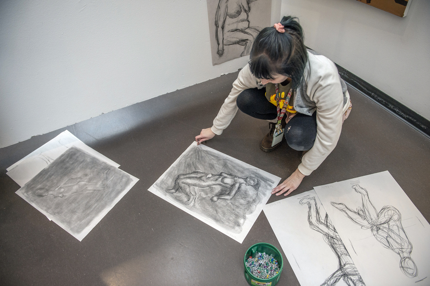 A student preparing to hang up their work for the young artist reception. 