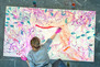 A student creating a large, abstract, colorful painting
