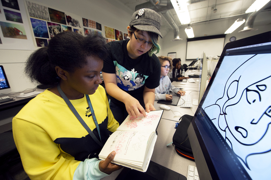 A Pre-College animation student and technical assistant look at sketches in the Animation lab. 