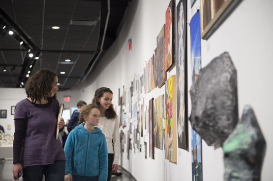 A student and their family view work displayed in the Scholastic Art and Writing exhibition. 