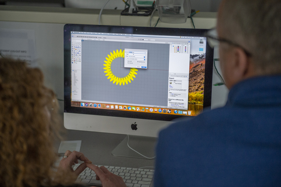 A teacher uses a computer to generate a 3D model for a jewelry piece. 