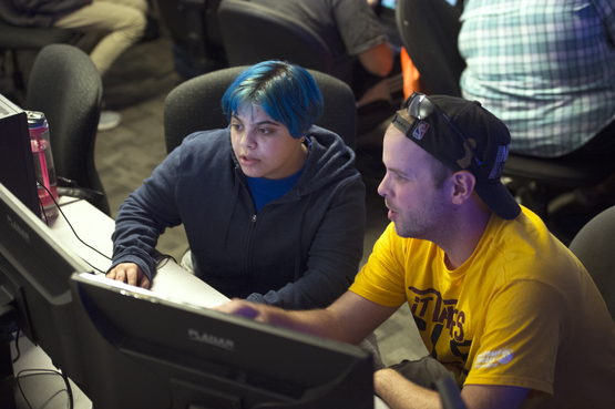 An instructor shows a Game Design student how to create game elements on a computer. 