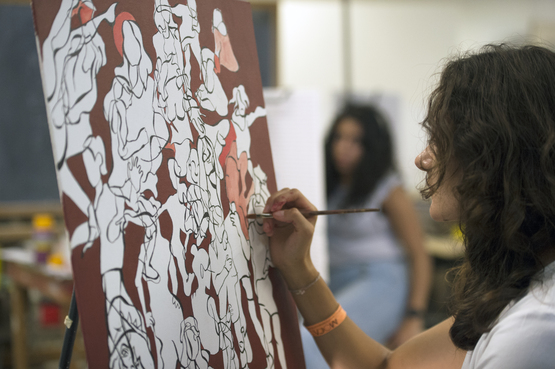 A student working on an abstract painting in class. 