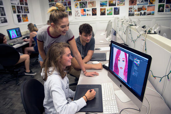 Students gather around a computer to look at a graphic design piece. 