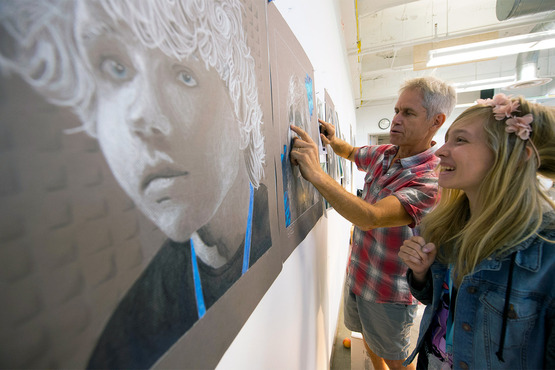 A student installs their work for the Pre-College exhibition with help from their instructor. 