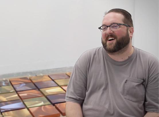 Dustin Smith with the oil paintings he made during his residency