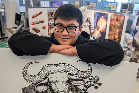 Student Junce Lu posing with artwork in his illustration studio