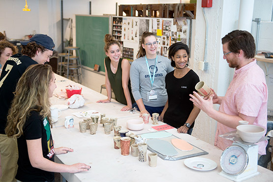 Matthew Pritchard teaching a small group of students around the Ceramics table